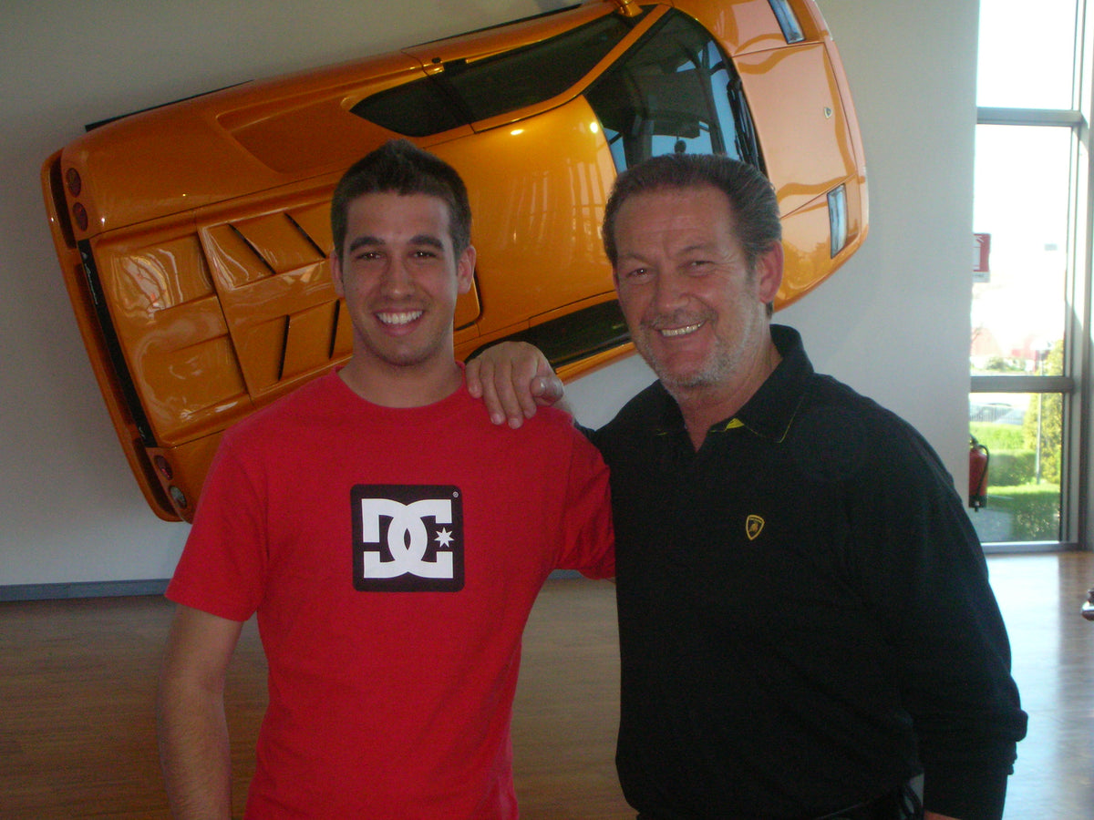 KOKE MUÑOZ Y VALENTINO BALBONI en interior frente a un LAMBORGHINI DIABLO naranja colocado inclinado en la pared.

