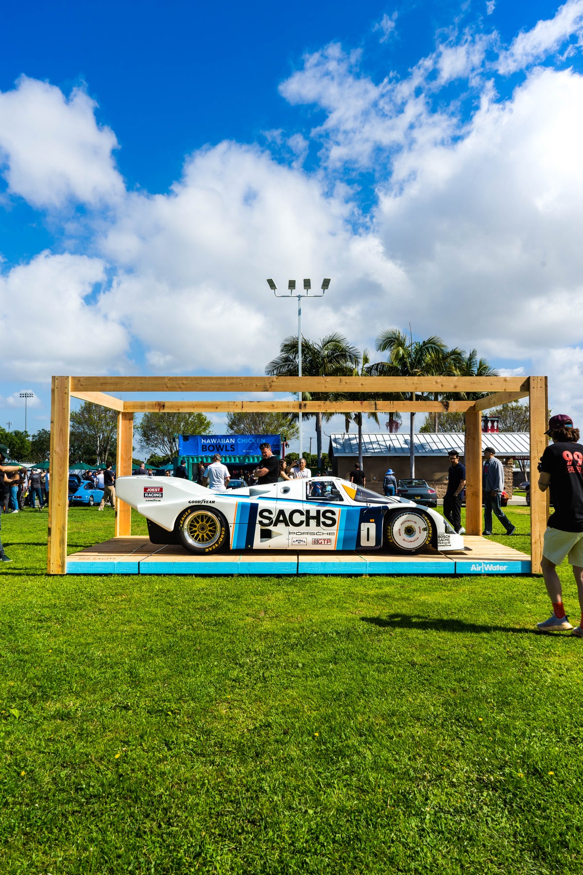 Porsche de carreras con decoración Sachs expuesto bajo una estructura de madera en un evento AIR/WATER