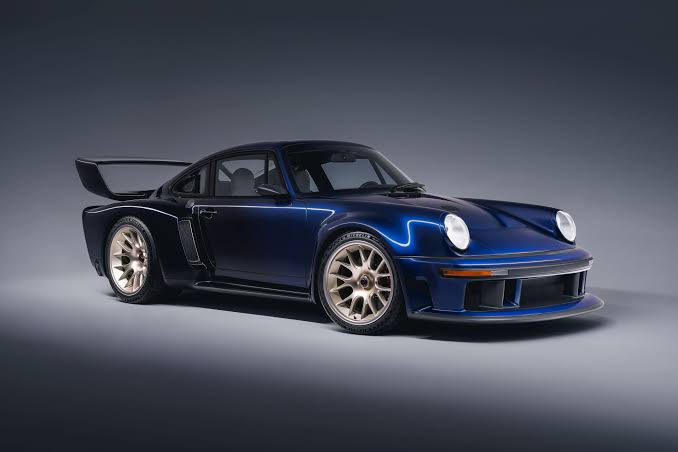 Coche deportivo azul con alerón grande y llantas deportivas